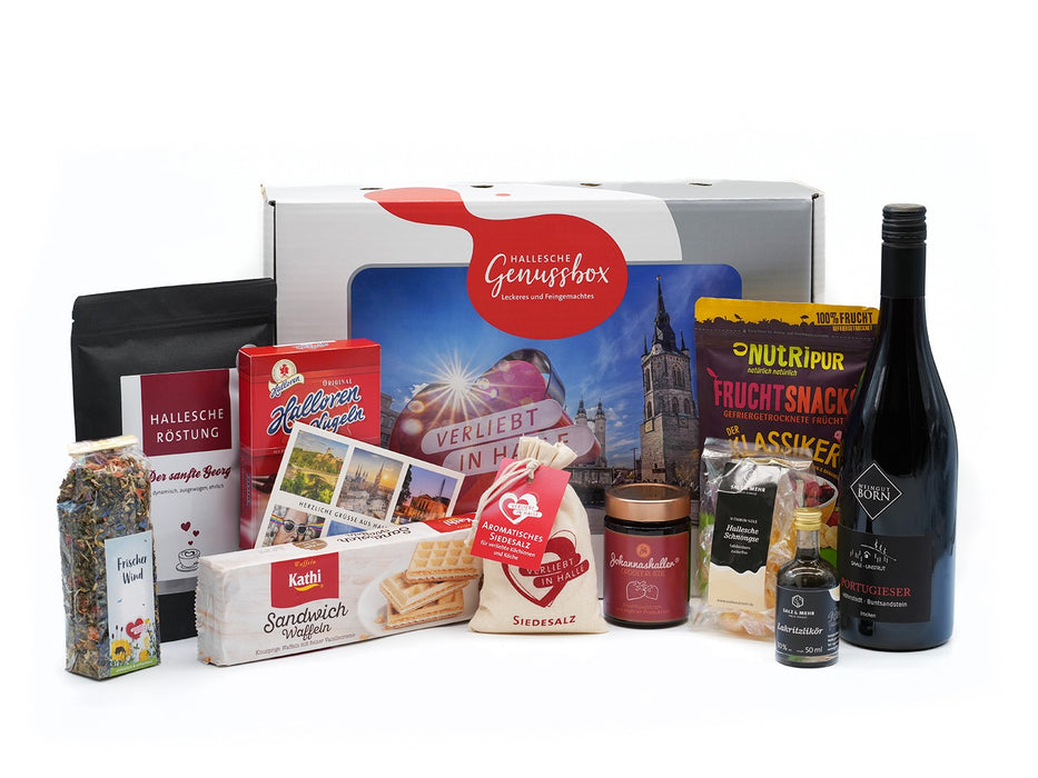 Die Hallesche Genussbox präsentiert sich auf weißem Grund, umgeben von Köstlichkeiten wie Kaffee, Waffeln, Früchtetee, Cracker, Marmelade, Honig, Original Halloren Kugeln, Siedesalz, Senf, Öl (Fläschchen) und Rotwein.