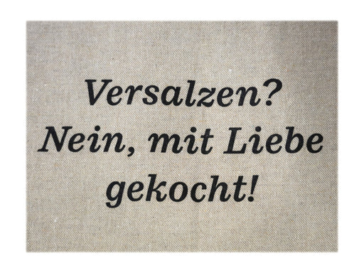 Ein beiger, strukturierter Hintergrund zeigt schwarzen deutschen Text: Versalzen? Nein, mit Liebe gekocht! Die elegante, kursive Schriftart sorgt für eine gemütliche Atmosphäre – die ideale Art, die Kochschürze „Versalzen? Nein, mit Liebe gekocht!“ zu präsentieren. Hergestellt aus recycelten Materialien. Es werden keine weiteren Bilder angezeigt.