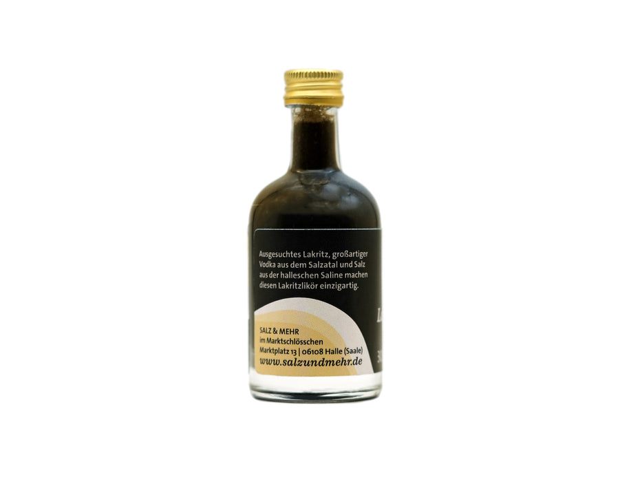 Eine kleine Glasflasche mit goldenem Schraubverschluss enthält Lakritzlikör klein, eine dunkle Flüssigkeit. Das Etikett auf der Vorderseite trägt den deutschen Text und die Webseite salzundmehr.de und beschreibt die Flüssigkeit als Salzatal Lakritzlikör. Die Flasche ist zentriert auf weißem Grund.