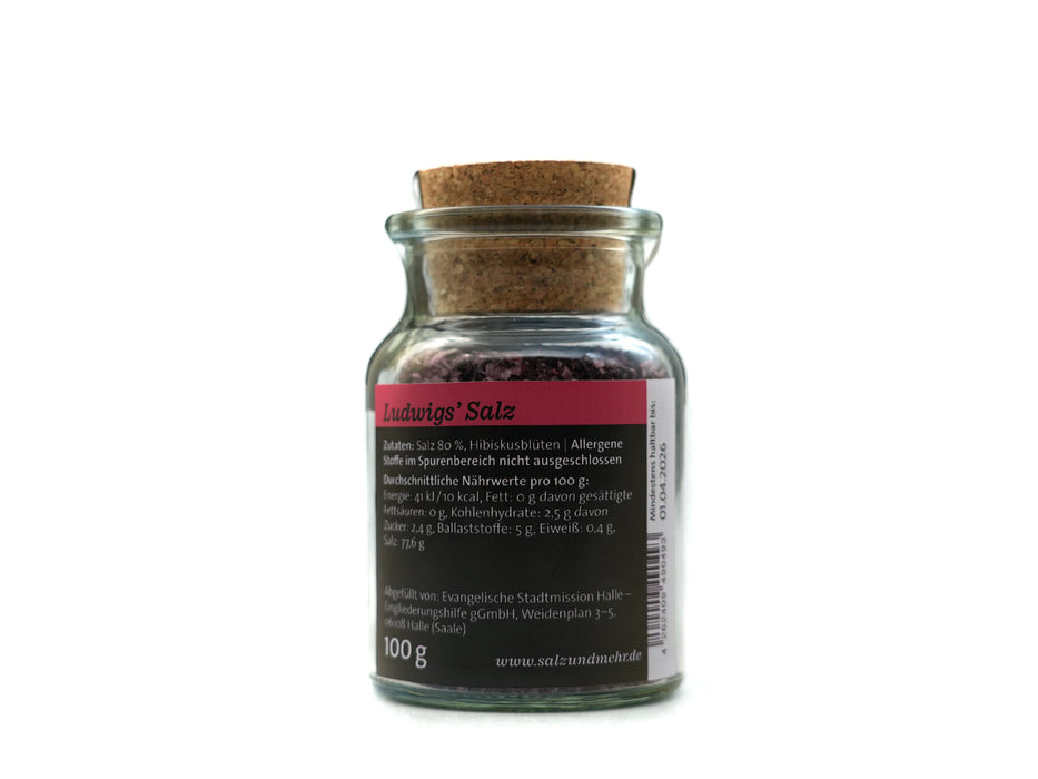 Ein kleines Glas mit Korkdeckel enthält Ludwigs Salz groß, ein rötliches Hibiskusblüten-Gewürzsalz. Das deutsche Etikett listet Zutaten, Nährwerte, 100-g-Gewicht und Hersteller auf. Perfekt für Sommersalate. Fotografiert vor weißem Hintergrund.