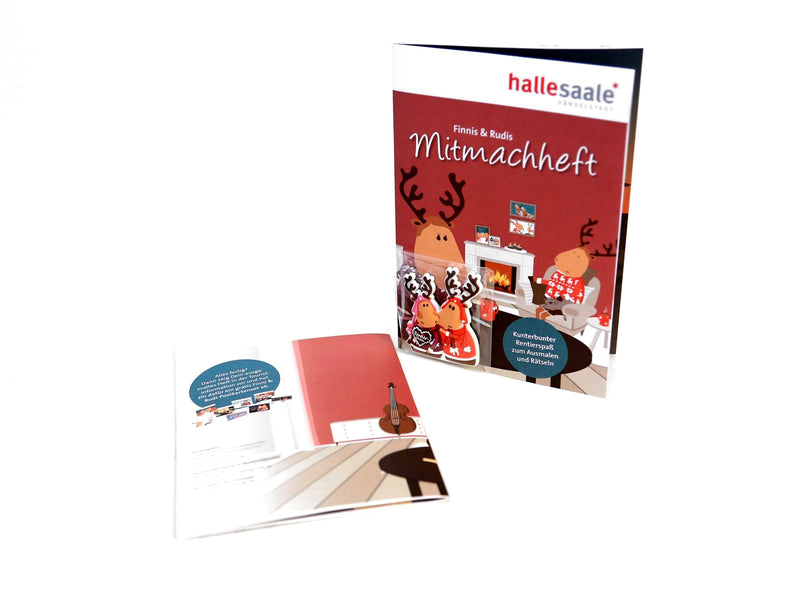 Abgebildet sind zwei Hefte: das stehende Mitmachheft „Finni & Rudi“ inkl. Magnet, das Comic-Rentiere in einem festlichen Wohnzimmer zeigt, und ein offenes, flach liegendes Heft mit illustriertem, weihnachtlichem Innenteil.
