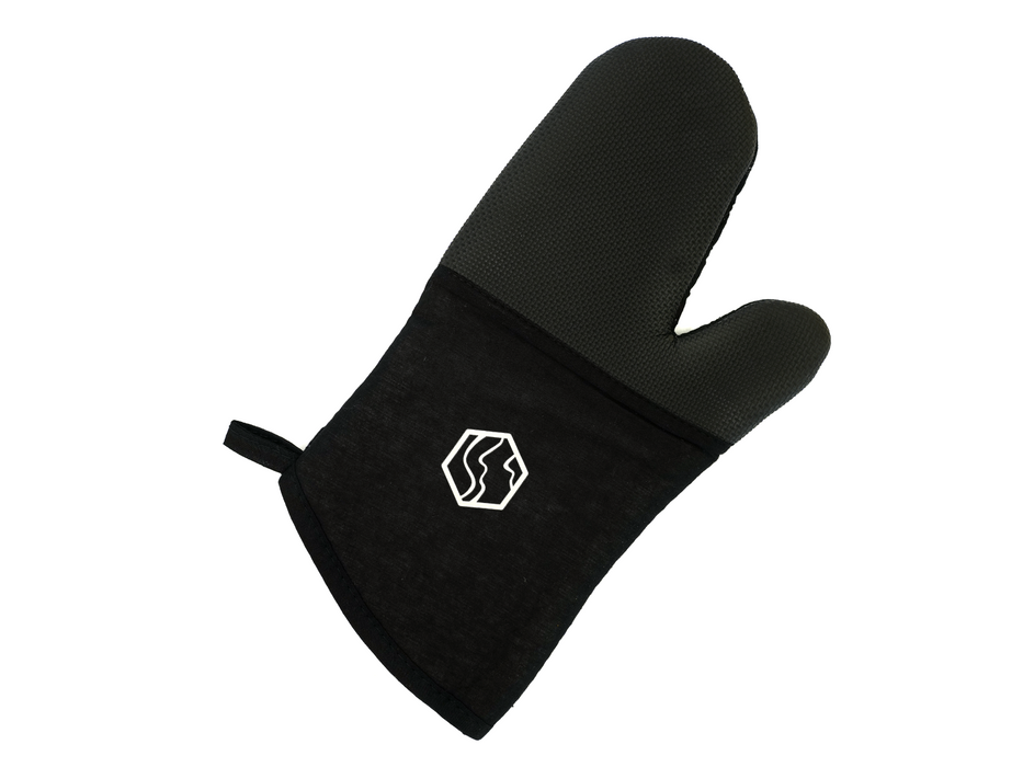 Der Ofenhandschuh von hallesaale* | Shop ist ein schwarzer Ofenhandschuh aus strapazierfähiger Baumwolle mit strukturiertem Griff, ergonomischem Design mit Daumenbereich, Aufhängeschlaufe und einem eleganten weißen geometrischen Logo in der Nähe der Manschette für die sichere und bequeme Handhabung heißer Gegenstände.