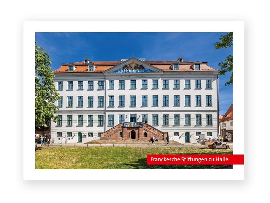 Die Postkarte „Franckesche Stiftungen“ zeigt ein großes weißes historisches Gebäude mit vielen Fenstern und rotem Ziegeldach in Halle (Saale), das hinter einer Rasenfläche steht. Eine breite Treppe führt zum Eingang. In der Nähe sind Menschen zu sehen, und ein rotes Schild mit der Aufschrift „Franckesche Stiftungen“ ist zu sehen.