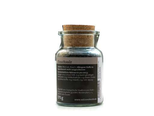 Ein Glas Rauchsalz groß mit Korkdeckel steht auf weißem Grund. Gefüllt mit dunklem Granulat eignet es sich ideal zum Grillen. Das graue Etikett zeigt 175 g und www.salzausdeutschland.de.