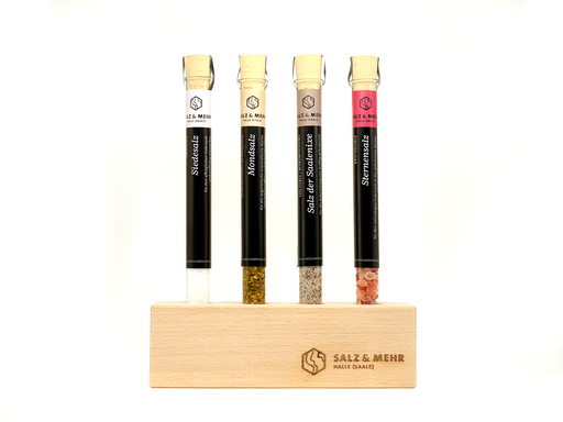 Der Reagenzglashalter von hallesaale* | Shop enthält Reagenzgläser mit Korkstopfen, die weiße, grüne, beige und rosa Salze enthalten. Jedes Röhrchen ist beschriftet und wird aufrecht in einem hellen Holzhalter mit den Gravuren „Salz & Mehr“ und „Halle (Saale)“ auf schlichtem weißem Hintergrund aufbewahrt.