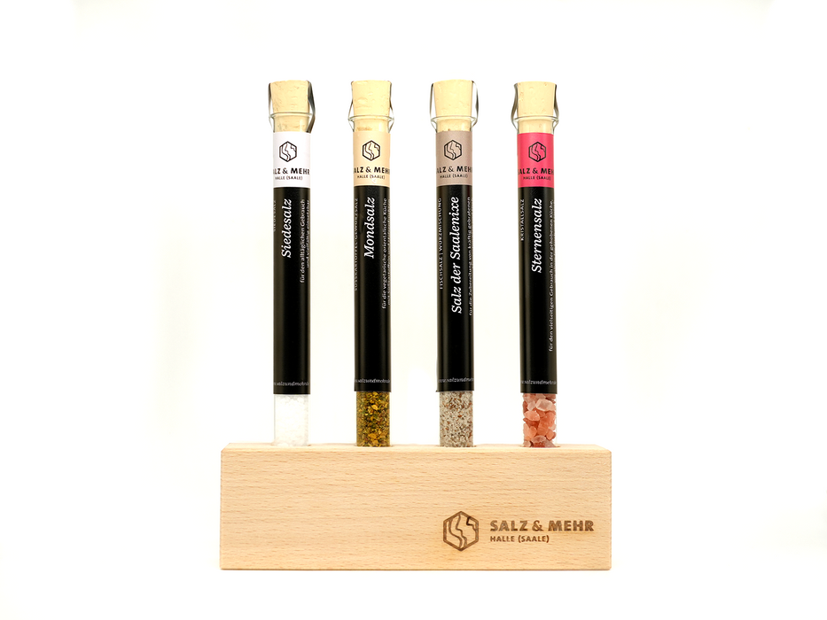 Der Reagenzglashalter von hallesaale* | Shop enthält Reagenzgläser mit Korkstopfen, die weiße, grüne, beige und rosa Salze enthalten. Jedes Röhrchen ist beschriftet und wird aufrecht in einem hellen Holzhalter mit den Gravuren „Salz & Mehr“ und „Halle (Saale)“ auf schlichtem weißem Hintergrund aufbewahrt.