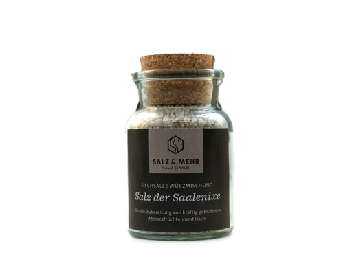 Das „Salz & Mehr-Bundle Salz der Saalenixe groß mit Salzschaufel“ besteht aus einem Glas mit grobem Salz, Korkdeckel und dunklem Etikett, ideal zum Würzen von Meeresfrüchten und Fisch. Das Glas enthält eine Salzschaufel und ist auf weißem Hintergrund abgebildet.