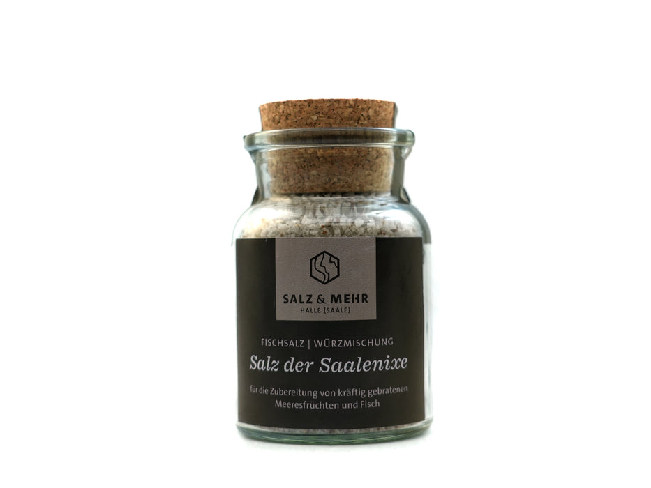 Das „Salz & Mehr-Bundle Salz der Saalenixe groß mit Salzschaufel“ besteht aus einem Glas mit grobem Salz, Korkdeckel und dunklem Etikett, ideal zum Würzen von Meeresfrüchten und Fisch. Das Glas enthält eine Salzschaufel und ist auf weißem Hintergrund abgebildet.