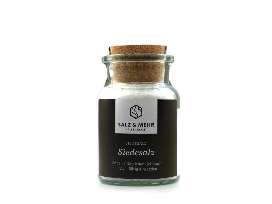 Ein großes Glas mit der Aufschrift „Siedesalz groß“ (99,9 g), gefüllt mit weißem Salz und mit einem Korken verschlossen, trägt ein schwarzes „Salz & Mehr“-Etikett mit dem Hinweis, dass es ohne Jod ist – perfekt für den täglichen Gebrauch. Das Produkt ist vor einem schlichten weißen Hintergrund fotografiert.