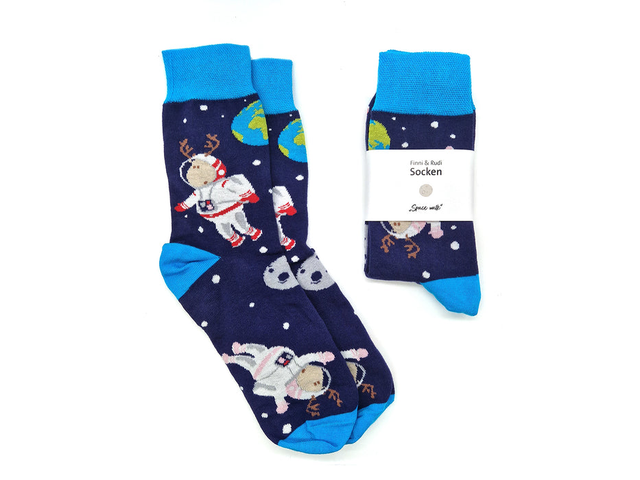 Zwei Paar marineblaue Socken „Finni & Rudi“ mit Astronauten- und Geweihmotiven, Planeten und Sternen. Diese kuscheligen Socken nach OEKO-TEX Standard 100 sind mit einem weißen Etikett mit der Aufschrift „Socken und Sparen mit!“ versehen.