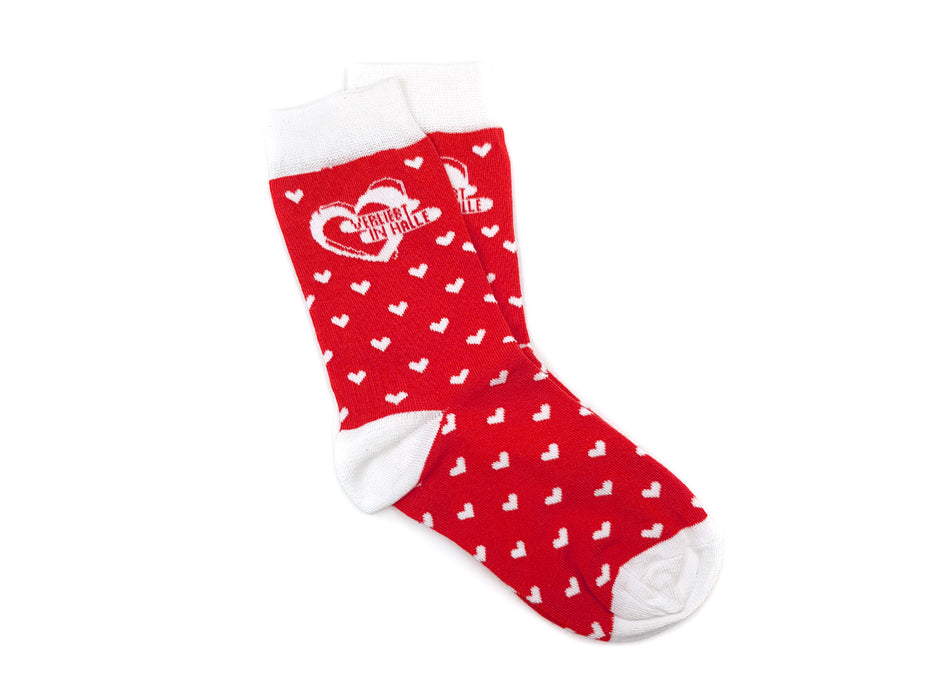 Die Socken „Verliebt in Halle“ sind kuschelige Bio-Baumwollsocken in Rot mit weißen Herzen, weißen Details und dem Schriftzug „While We Wait“ im Herzdesign. Produziert in Europa und liebevoll auf weißem Hintergrund arrangiert.