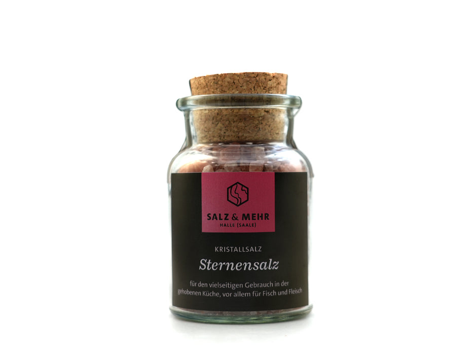 Ein Glasgefäß mit Korkdeckel enthält rosa Kristallsalz mit der Aufschrift „SALZ & MEHR“. Auf dem schwarzen Etikett steht „Kristallsalz Sternensalz“ und Informationen auf Deutsch. Produkt: Salz & Mehr-Bundle „Sternensalz groß mit Salzschaufel“.
