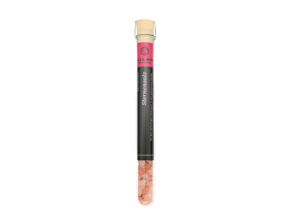 Sternensalz klein wird in einem klaren Glasfläschchen mit rosa Salzstücken geliefert und mit einem Korken verschlossen. Das schwarze Etikett mit rosa Akzenten trägt den deutschen Text, darunter „Sternensalz“. Ideal für die gehobene Küche, steht das Fläschchen aufrecht auf weißem Untergrund.