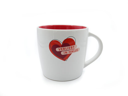 Die Tasse „Verliebt in Halle“ (weiß-rot) ist ein weißer Becher mit roter Innenseite. Auf der Vorderseite ist vor einem schlichten weißen Hintergrund ein kräftiges rotes Herz und „VERLIEBT IN HALLE“ in weißen Buchstaben abgebildet.