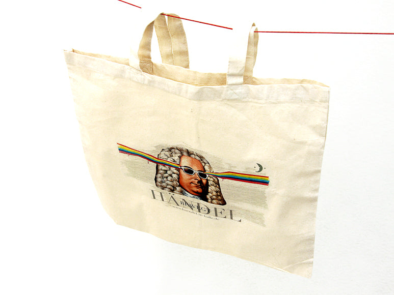 Der Leinenbeutel „Graffiti-Händel“ ist ein beigefarbener Fairtrade-Baumwollbeutel, der an einer roten Schnur auf weißem Hintergrund hängt. Er zeigt den Komponisten Händel mit Sonnenbrille und einem Regenbogenstrahl im Haar. Darunter ist „HANDEL“ aufgedruckt.