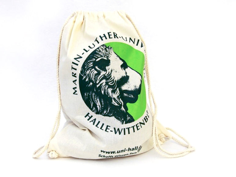 Der beige Turnbeutel „Martin-Luther-Universität“ zeigt einen schwarzen Löwenkopf auf einem grünen Kreis, umgeben von „Martin-Luther-Universität Halle-Wittenberg“ und unten „www.uni-halle.de“.