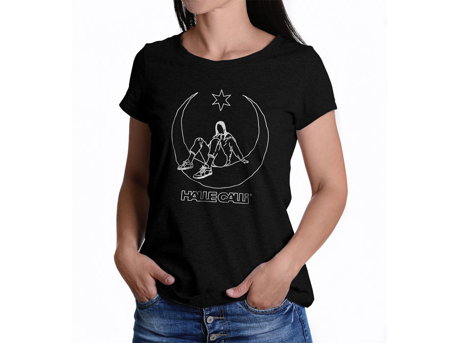 Eine Frau trägt das T-Shirt „HALLEGALLI® – SCHICKSE“ in Schwarz aus Bio-Baumwolle. Es zeigt eine minimalistische Strichzeichnung, eingerahmt von Halbmond und Stern, darunter den fettgedruckten „HALF CALIF“-Schriftzug. Die bequeme mittlere Passform ist für Damen.