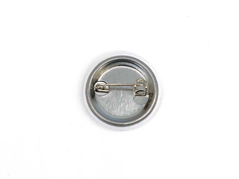 Der Button „Verliebt in Halle“ ist eine runde Anstecknadel aus Metall. Die Rückseite ist mit einer waagerechten Sicherheitsnadel zur sicheren Befestigung an der Kleidung versehen und befindet sich auf einem schlichten weißen Hintergrund.