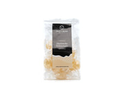 Der transparente Beutel der Halleschen Schnongse – Salzbonbons „7-Kräuter“ der Soole eG zeigt ein weißes Etikett mit geometrischem Logo und Text und präsentiert vegane Bonbons, einzeln in transparentem Papier verpackt. Ein Website-Link befindet sich unten. Die Verpackung ist schlicht und übersichtlich.