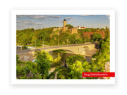 Eine Steinbrücke mit Skulpturen überspannt einen Fluss in Halle (Saale). Auf einem bewaldeten Hügel dahinter erheben sich die mittelalterlichen Mauern und der Turm der Burg Giebichenstein. Leicht bewölkter Himmel. Rotes Etikett: Postkarte "Burg Giebichenstein".