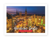 Die Postkarte „Hallescher Weihnachtsmarkt“ zeigt einen festlichen Markt auf dem Halleschen Marktplatz in Halle (Saale) mit funkelnden Lichtern, geschmückten Buden und Bäumen, eingerahmt von Kirchtürmen. Text: Herzliche Grüße Hallescher Weihnachtsmarkt.