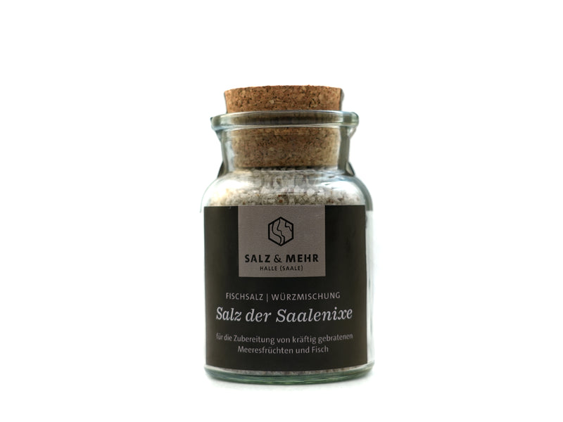 Das „Salz & Mehr-Bundle Salz der Saalenixe groß mit Salzschaufel“ besteht aus einem Glas mit grobem Salz, Korkdeckel und dunklem Etikett, ideal zum Würzen von Meeresfrüchten und Fisch. Das Glas enthält eine Salzschaufel und ist auf weißem Hintergrund abgebildet.