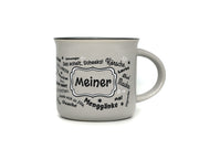 Graue Keramiktasse in klassischer Emaille-Becher-Form mit schwarzem Innenrand. Auf der Frontseite befindet sich der Schriftzug „Meiner“ in einem geschwungenen Rahmen, umgeben von halleschen Mundart-Begriffen wie „Körsche“, „Mauke“ und „Menggänke“.