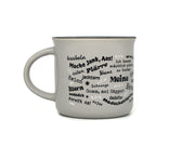 Graue Keramiktasse in klassischer Emaille-Becher-Form mit schwarzem Innenrand. Auf der Frontseite befindet sich der Schriftzug „Meiner“ in einem geschwungenen Rahmen, umgeben von halleschen Mundart-Begriffen wie „Körsche“, „Mauke“ und „Menggänke“.