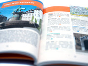 Eine Nahaufnahme des hell erleuchteten Taschenbuchs „Halle (Saale)“ – Stadtführer zeigt eine Seite über die Südliche Altstadt mit einem Foto historischer Wahrzeichen, deutschem Text und einer Karte; In den nahegelegenen Abschnitten sind der Bergzoo und das Händel-Geburtshaus hervorzuheben.